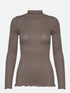 Diese Rollkragenbluse besticht durch ihre Raffinesse mit ihren gewellten Kanten an Halsausschnitt und Saum und verleiht jedem Outfit einen Hauch von Eleganz.